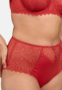 Ensemble de lingerie en dentelle rouge avec des motifs géométriques complexes, des bords festonnés et des accessoires en métal doré. Matériau doux mêlé aux détails en dentelle.