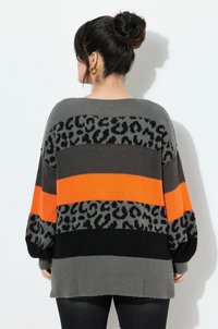 Strickpullover mit horizontalen Streifen in Grau, Orange und Schwarz, der im oberen Bereich ein Leopardenmuster aufweist und eine lockere Passform hat.