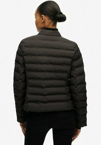 Czarna kurtka puchowa z pikowanym wzorem, z kołnierzem stójkowym i dopasowanym krojem. Gładka faktura, brak widocznych elementów metalowych lub wzorów.
