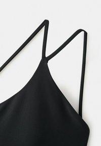 Zwarte spaghetti band met V-hals detail van gladde stof op een witte achtergrond.