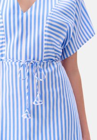 Sukienka w niebiesko-białe paski, z dekoltem w kształcie litery V, szerokimi rękawami, wiązaniem w talii z frędzlami oraz lekką tkaniną.