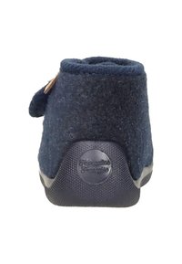 Navy felt slipper with a rounded back, textured surface, and a rubber sole. Features a small tab and branded circular accent at the heel.