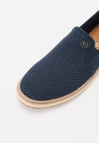 Scarpa slip-on navy realizzata in tessuto a rete, con una soletta in sughero naturale e una suola avvolta in juta. Presenta un piccolo logo metallico decorativo.