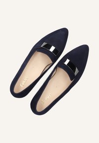 Marineblauwe suède instappers met een driehoekige vorm, voorzien van een glanzende zwarte accentband over de bovenkant en een beige binnenzool.