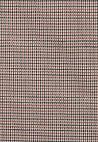 Tissu pied de poule présentant un motif texturé en noir, blanc et rouille. Le design à petite échelle crée une apparence uniforme.