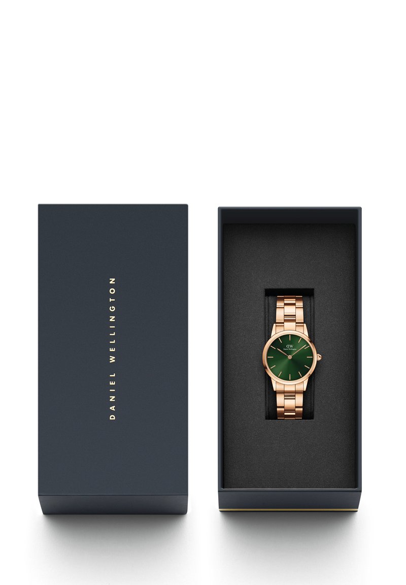 Roségoldenes Metall-Armbanduhren mit grünem Ziffernblatt, präsentiert in einer dunkelblauen Box mit weicher schwarzer Auskleidung. Die Uhr verfügt über ein Gliederarmband-Design.