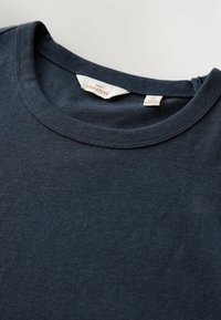 Granatowy bawełniany T-shirt z okrągłym dekoltem, z metką na kołnierzyku z napisem "NEXT SIGNATURE". Gładka faktura i brak widocznych wzorów.