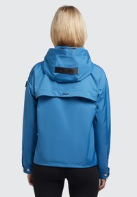 Blue waterproof jacket with a hood, featuring a back vent, Khujo logo patch, and snap button cuffs. Smooth texture and durable design.