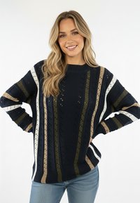 Granatowy sweter w paski z poziomymi wzorami w kolorach kremowym, oliwkowym i beżowym. Posiada dzianą fakturę i okrągły dekolt. Luźny krój, długie rękawy.