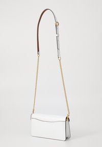 Vit läderaxelväska med en elegant design, som har en guldkedjestrap och en kontrasterande brun justerbar axelrem.