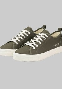Olivgrüne Segeltuch-Sneaker mit weißen Schnürsenkeln, Gummisohlen und einer Lasche an der Rückseite. Der Text auf der Seite lautet: "Deine einzige Grenze ist dein Verstand."