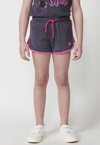 Pantaloni corti grigi con bordi rosa e cordoncino, abbinati a una maglietta scura con un design floreale e glitter. Indossati con sneakers bianche.