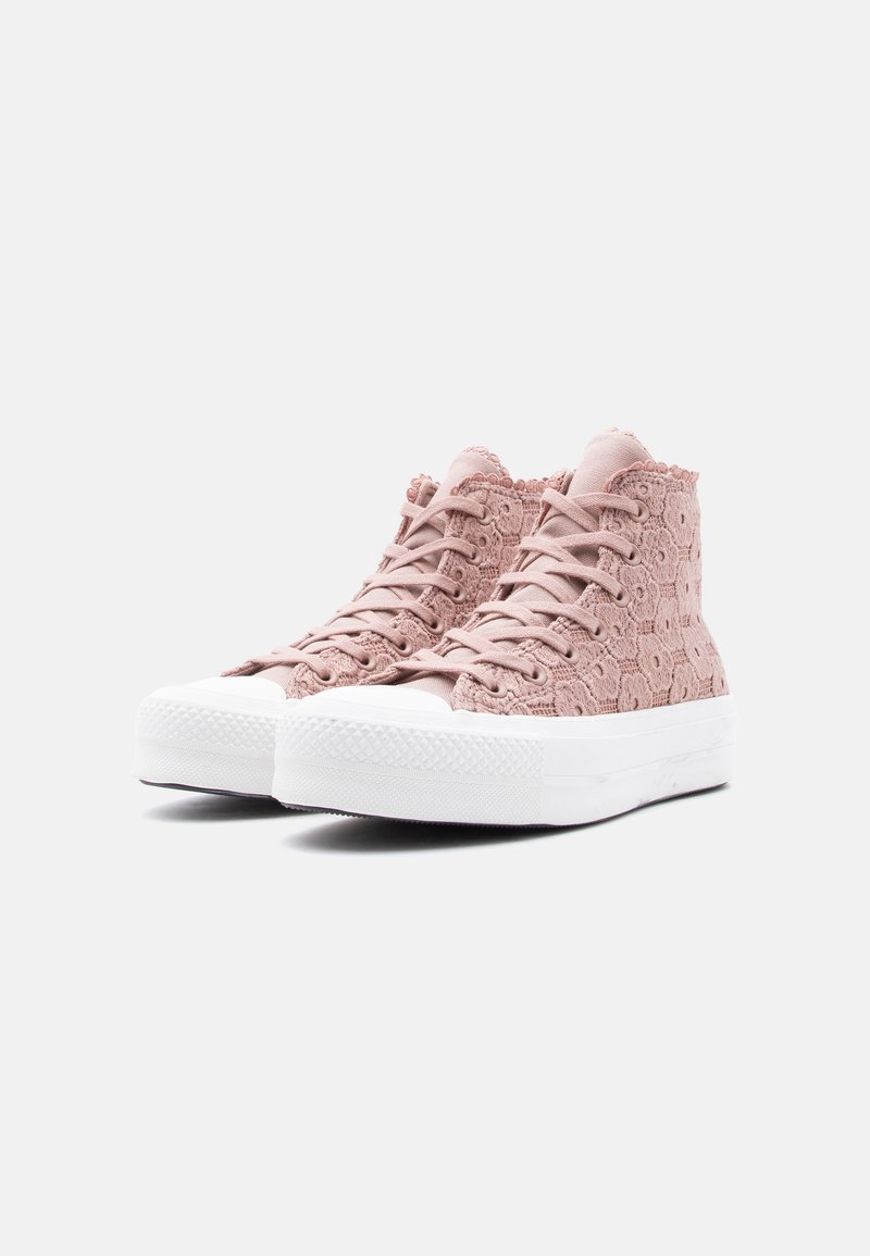 Sneakers alte rosa con pizzo, suole spesse in gomma bianca, lacci e dettagli con motivi floreali, viste a tre quarti.