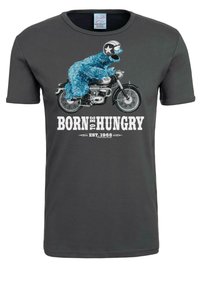 Graues Baumwoll-T-Shirt mit einem Grafikdruck eines blauen, pelzigen Charakters, der einen Helm auf einem Motorrad trägt, accompanied by dem Text "GEBOREN UM GIERIG ZU SEIN."
