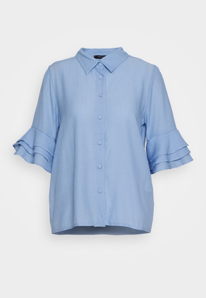 Ljusblå skjorta med krage. Korta ärmar med lager av volanger. Tillverkad av texturerat tyg, med en lös passform och rak fåll.