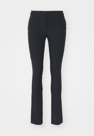 Pantalons noirs extensibles avec un design ajusté, présentant une texture lisse, une coupe droite et de petites fermetures éclair sur le côté à l'ourlet.