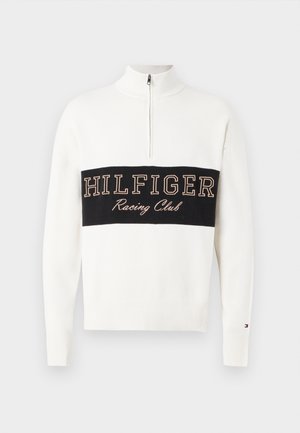 Sweater branco com fecho de zíper no pescoço e punhos canelados, apresentando uma faixa horizontal preta com "HILFIGER Racing Club" bordada em bege. Textura de malha macia.