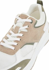 Baskets blanches et beiges avec des panneaux en mesh et suède, lacets blancs, col rembourré et semelle blanche épaisse.