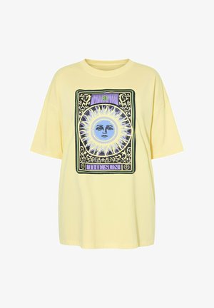 Żółta oversize koszulka z wzorem karty tarota z niebieskim słońcem z twarzą oraz tekstem "THE SUN" w fioletowych i czarnych detalach.