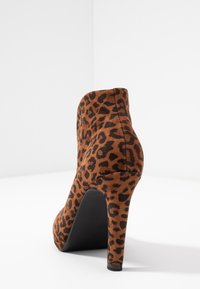 Bottines à talons hauts en daim marron à imprimé léopard, avec un bout pointu et une plateforme noire élégante, dotées d'un talon aiguille élancé.