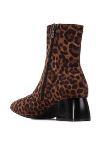 Botín de tobillo con estampado de leopardo, hecho de un tejido suave, con una cremallera lateral y una suela corta de tacón negro con forma curva.