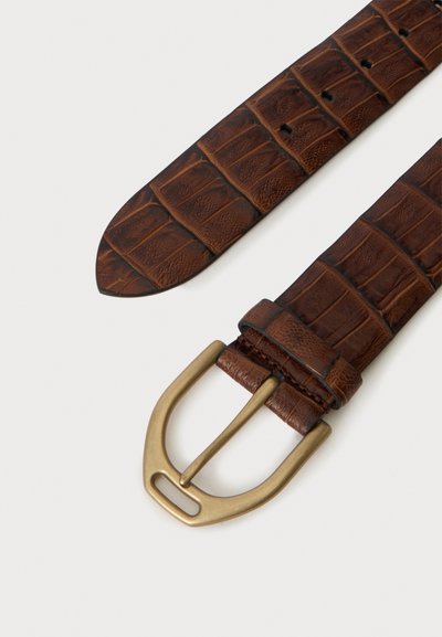 Ceinture en cuir marron texturé avec une boucle en métal doré sur un fond clair, montrant la pointe et les trous de la ceinture.