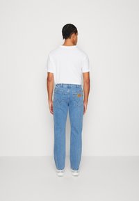 Vaqueros de denim azul claro con corte recto, que presentan una etiqueta de cuero en la parte trasera de la cintura y dos bolsillos traseros con puntadas en zigzag.