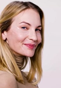Hydraterende oogpatches aangebracht onder heldere ogen, lichte huid met een gladde textuur, omlijst door lang, recht, blond haar en een geribbelde tan top.