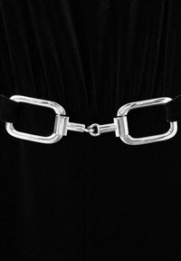 Prenda de terciopelo negro con un cinturón de hebilla metálica plateada ancha. La hebilla tiene forma rectangular y un acabado pulido, lo que realza el diseño.