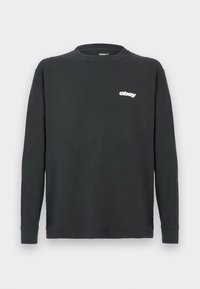 Camisola preta de manga longa feita de algodão, com um decote redondo e um logótipo branco "obey" no lado esquerdo do peito. Textura suave, ajuste descontraído.