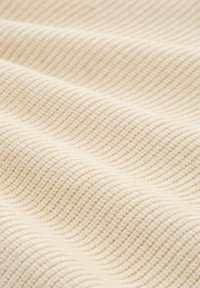 Kremowy materiał prążkowany o miękkiej, falistej fakturze pokazany z bliska.