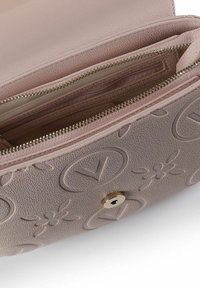 Borsa strutturata in pelle rosa chiaro con motivi floreali in rilievo, dotata di cerniera argentata e chiusura a scatto metallica circolare.