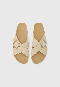 Sandali infradito in suede beige con fasce incrociate, dotati di una fibbia dorata e di una suola testurizzata per il massimo comfort.
