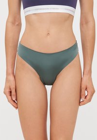 Høyt liv bikini shorts i myk, matt grønn stoff. Har en jevn tekstur og minimale sømmer, med et enkelt design og ingen synlige mønstre.