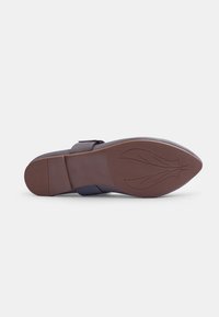 Suela de zapato con forma redondeada, material de goma marrón, patrón texturizado y diseño sutil de hojas. Presenta una correa de tela azul para mayor soporte.