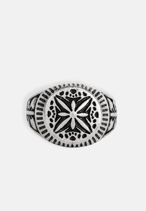 Hõbedane sõrmus, millel on ovaalne kuju, keerukate tähepuudutuste ja ümmarguste mustritega, tekstureeritud riba ning kontrastsed tumedad aktsendid.