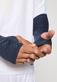 Ναυτικές συμπιεστικές μανικέτες με υφές, εφαρμοστό σχέδιο και θύρες για τα δάχτυλα. Το υλικό φαίνεται ελαστικό και απορροφητικό υγρασίας.