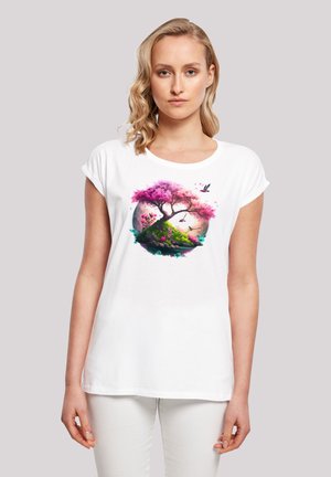 Weißes Baumwoll-T-Shirt mit umgeschlagenen Ärmeln, das ein farbenfrohes Motiv eines rosa Baums, von Grün umgebenen Pflanzen und Vögeln vor einem kreisförmigen Hintergrund zeigt.