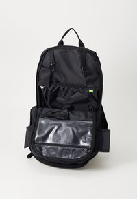 Black backpack with a zipper closure, featuring a mesh pocket on the front, multiple interior compartments, and a sturdy handle.