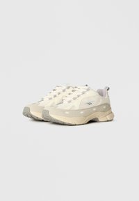 Bēšas sporta kurpes ar teksturētu auduma virsmu, pelēkiem zāģētu zamša akcentiem, polsterētu mēli un veidotu gumijas zoli ar raksturīgu protektoru.