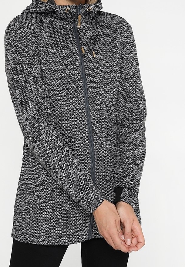 Strikjakke i grå og sort med hætte, fuld lynlås og elastiske manchetter. Har et struktureret mønster og trædetaljer på lynlåsen.