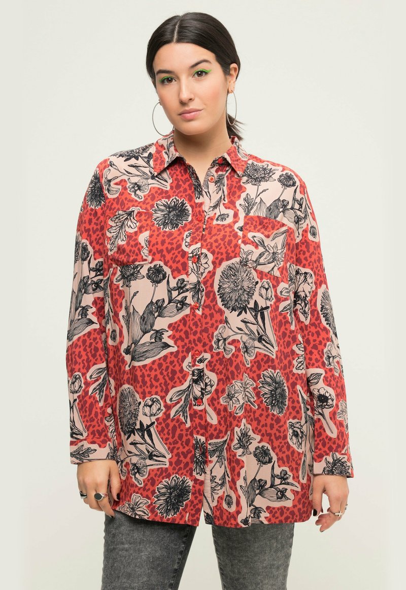 Camicia a maniche lunghe a bottoni rossi e crema con motivi floreali e animali, dotata di taschino sul petto. Tessuto dalla texture liscia.