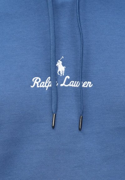 Μπλε ύφασμα με λευκό κεντημένο λογότυπο Ralph Lauren που απεικονίζει έναν παίκτη πόλο πάνω σε άλογο, μαζί με κορδόνια φούτερ σε ίδιο μπλε χρώμα με μεταλλικές άκρες.