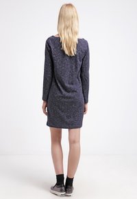 Abito a maniche lunghe di colore grigio scuro con una vestibilità comoda, lunghezza al ginocchio, texture sottile e scollatura ampia. Abbinato a calze nere e sneaker metalliche.