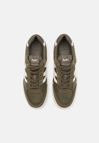 Sneaker verdi e bianchi con una tomaia in pelle textured, chiusura con lacci e logo MK in evidenza. Presentano una linguetta e una cavigliera imbottite.