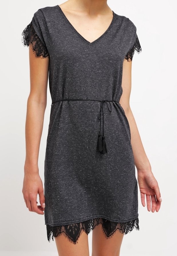 Robe grise à col en V avec des manches courtes, présentant une bordure en dentelle noire au niveau de l'ourlet et des manches, ainsi qu'une taille nouée avec des accents de frange.
