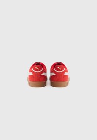 Røde ruskinds sneakers med hvide stofdetaljer og en gummisål. Har et logo på hælen og en klassisk lav-top design.