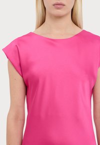 Fuksia saten majica s kratkim, strukturiranim rukavima i širokim izrezom, s glatkom, sjajnom teksturom. Nema vidljivih uzoraka ili naglasaka.