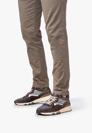 Baskets marron et grises avec un mélange de textures comprenant du daim, du mesh et du tissu. Elles présentent une semelle épaisse et des détails en zigzag.