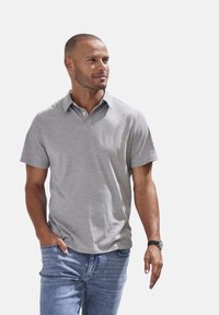 Graues Polohemd aus glattem, leichtem Stoff mit kurzen Ärmeln und Kragen, kombiniert mit lässigen blauen Jeans. Einfaches, sauberes Design.